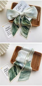 Détail du foulard plissé en soie avec motif de lavis vert et bords d'ourlet vert foncé