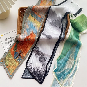 Trois foulards plissés étroits avec motifs paysagers présentés sur un panier tressé