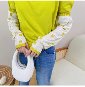 Detail of elastic cuffs on white arm sleeves with yellow cartoon cat prints