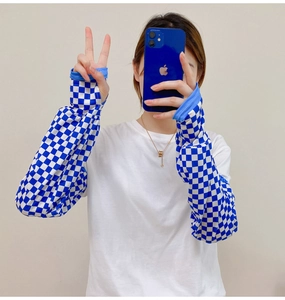 Detail of white long sleeve shirt featuring a blue and white checkerboard sleeve pattern