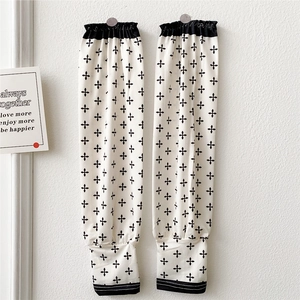 Close-up of cream sun protection sleeves with black cross-star pattern and elastic cuffs