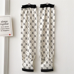 Detailed close-up of white sun protection sleeves with black geometric letter patterns