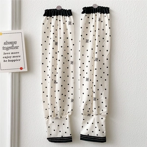 Detail of white sun protection sleeves with black dot pattern and elasticated cuffs
