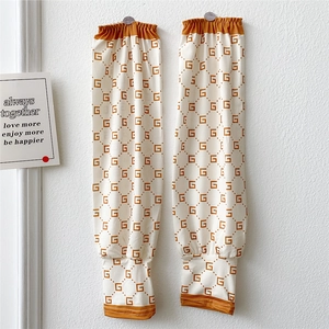 Detail of beige sun protection sleeves with repeating G-pattern and elastic brown cuffs
