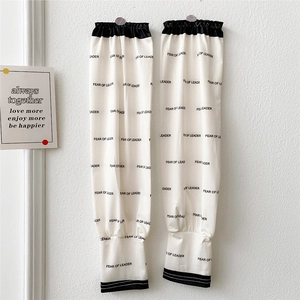Detail of off-white cooling arm sleeves with black FEAR OF LEADER letter print and elastic cuffs