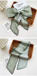 Detail of light green pleated silk scarf with elegant brand lettering and textured finish