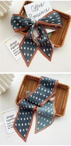 Detail of pleated navy blue polka dot silk scarf with contrast orange edge and soft texture