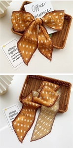 Detail of caramel polka dot pleated silk scarf shown as a bow knot and draped flat
