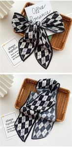 Detail of pleated long scarf featuring a classic black and white checkerboard pattern