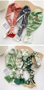 Detailed view of various colorful printed silk twilly scarves with geometric and floral patterns