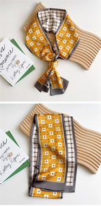 Detail of floral yellow silk scarf with vintage houndstooth pattern tied on wooden stand