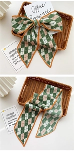 Detail of pleated long scarf featuring a vintage checkerboard pattern in muted green and white