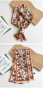 Close-up of cream skinny scarf with red paisley print and polka dot border details