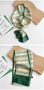 Macro view of green and white geometric silk scarf tied around a wooden display board