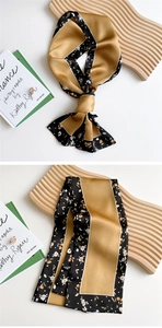 Detail of elegant mustard and black floral silk scarf draped over minimalist books