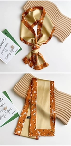 Close-up of orange and beige narrow silk scarf with delicate white floral patterns