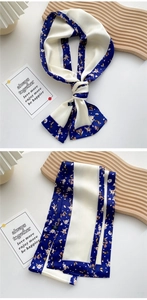 Close-up of narrow silk floral scarf with navy blue borders and elegant fold detail