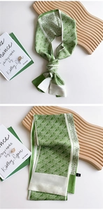 Detail of green and beige geometric silk scarf showing textured fabric and pattern