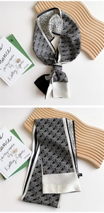 Detail of black and white geometric silk scarf draped on a minimalist display