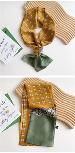 Macro detail of patchwork twilly scarf showing yellow geometric print and green silk texture