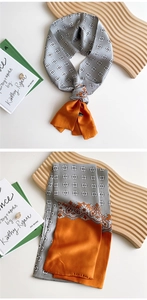 Detail of grey and orange satin silk scarf featuring paisley patterns and geometric texture