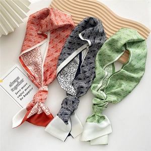 Three elegant skinny silk scarves with geometric prints on a minimalist white backdrop