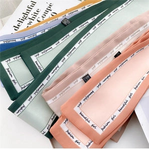 Detailed macro view of 100% polyester silk-feel scarves in various pastel colors