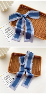 Detail of blue satin ribbon scarf with fashion text in a woven tray setup