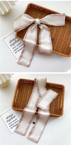 Detail of pink and cream patchwork silk scarf tied as a bow and laid flat on a basket