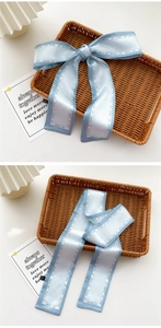 Close-up of light blue satin hair ribbon with fashion girl print on a woven tray