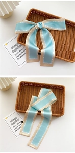 Detail of light blue narrow satin scarf tied in a bow showing the sleek silk texture