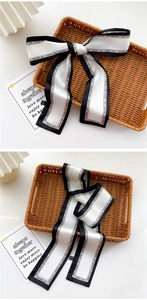 Detail of elegant black and white silk ribbon scarf with Fashion Girl print and bow tie