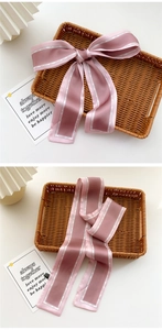Close-up of pink satin skinny scarf showing smooth silk texture and fashion lettering