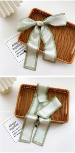 Detail of light green and white silk scarf tied in a bow with fashion text printing