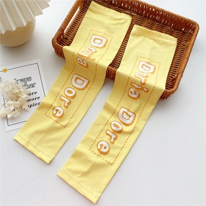 Close-up of yellow sun protection arm sleeves with Doria Dore print on a woven basket