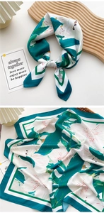 Detailed close-up of a white silk scarf with green botanical prints and silky texture