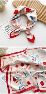 Detailed close-up of a floral silk scarf with red tulips and navy leaves on cream background