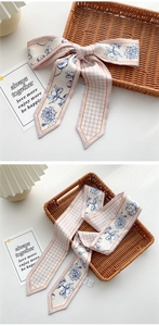 Detailed macro view of long pink twilly silk scarf with floral and checkerboard patterns