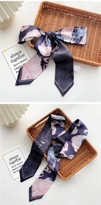 Detail of slim silk scarf with pink roses and blue architecture prints for hair styling