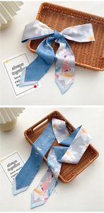 Detail of light blue narrow silk scarf with daisy and moon patterns tied as a bow