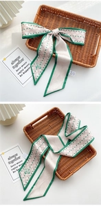 Detail of pink plaid skinny scarf with green borders and butterfly print on a tray