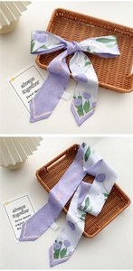 Detail of a thin purple tulip silk scarf tied as a bow on a woven basket