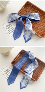 Detail of blue floral satin skinny scarf with double-sided rose pattern and elegant lettering