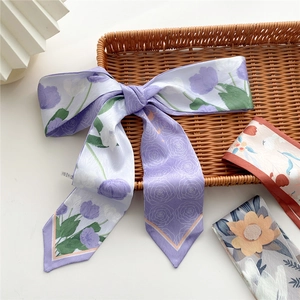 Narrow floral lavender silk scarf with purple tulips and roses tied in a bow on wood tray
