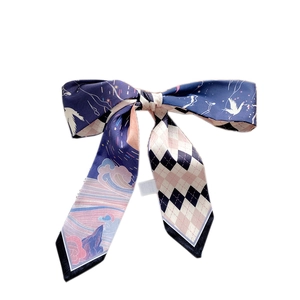 Narrow silk scarf with crane and diamond patterns tied in a bow on a white background