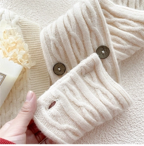 Detail view of cream cable knit scarf featuring dark wood buttons and soft wool texture