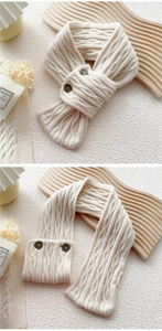 Detail of cream cable-knit scarf featuring soft texture and dual button closure