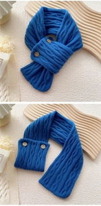 Detail of blue cable-knit scarf featuring two round wooden buttons and warm textured wool
