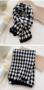 Close-up of black and white diamond lattice knitted scarf with Paris label and soft texture
