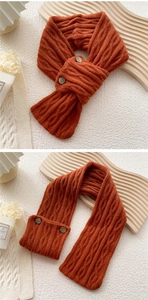 Detail of orange cable knit scarf with vintage wood buttons on textured surface